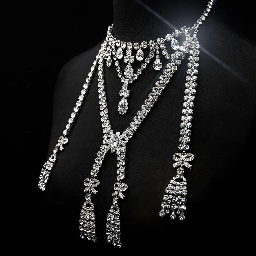 A handcrafted silver finish necklace with Austrian crystals, featuring multiple chains and tassels, displayed on a mannequin.