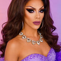 Woman wearing a sparkling necklace and purple dress against a pink and purple gradient background
